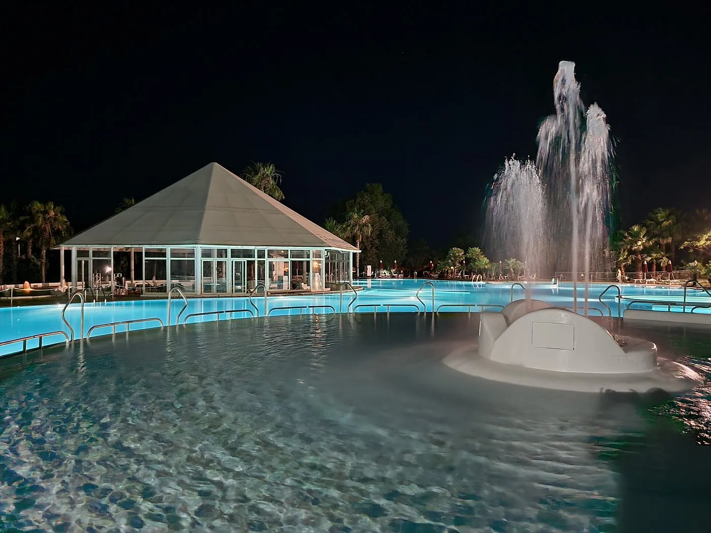 Piscina illuminata di sera con gazebo e fontana zampillante