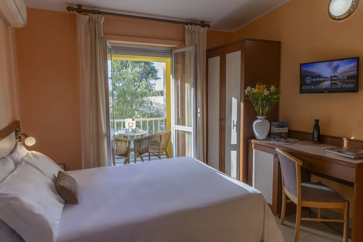 Camera con letto matrimoniale, scrivania, TV e porta-finestra sul balcone