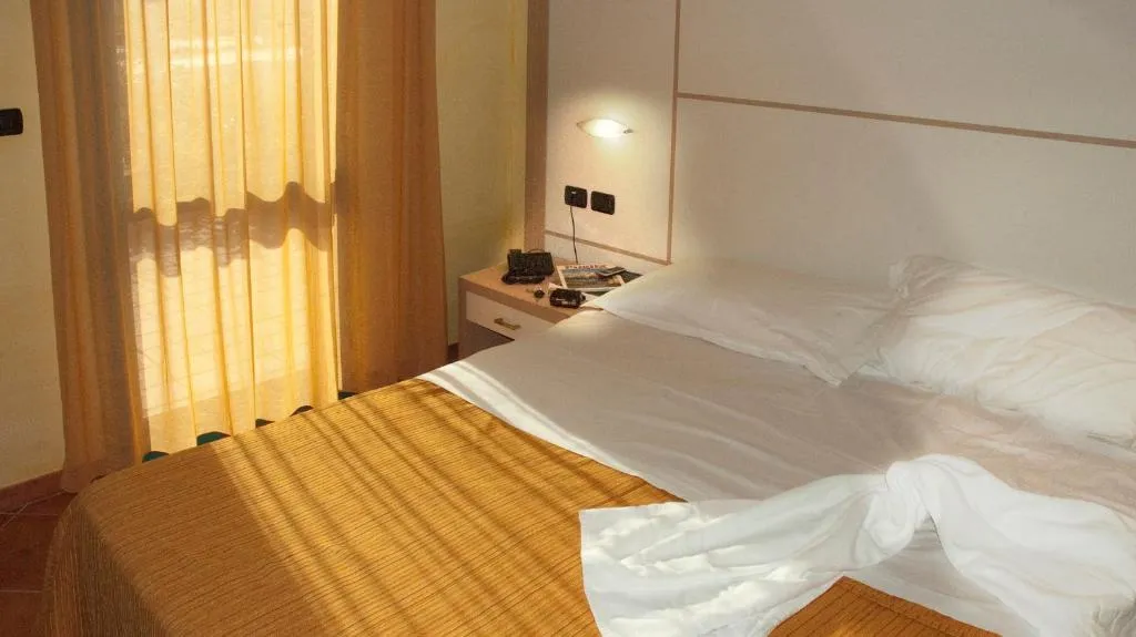 Camera con letto matrimoniale e tende illuminate dalla luce naturale