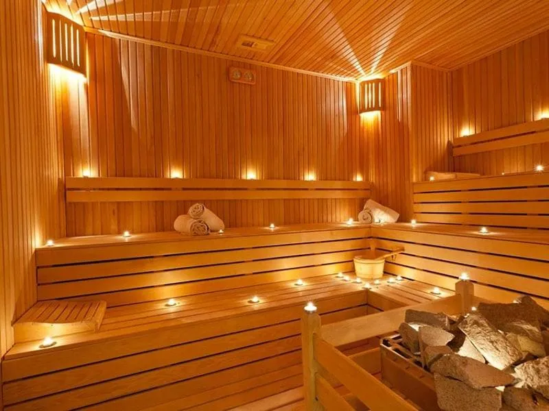 Sauna in legno con illuminazione soffusa e asciugamani arrotolati