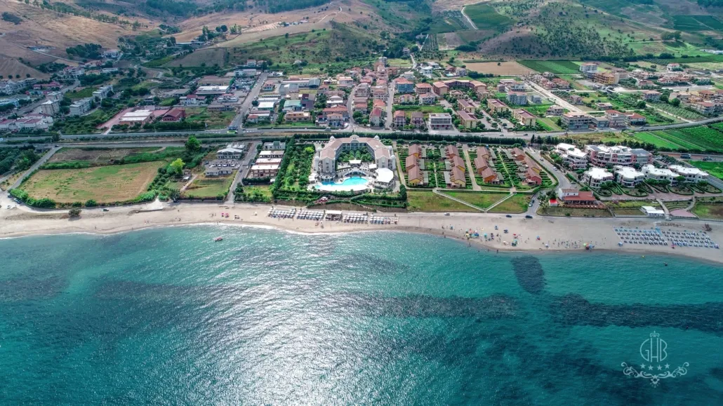 Panoramica aerea dell'hotel con piscina, spiaggia e paesaggio collinare circostante