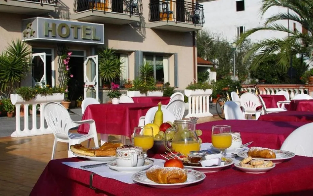 Tavolo della colazione all'aperto con cornetti e succhi davanti all'hotel