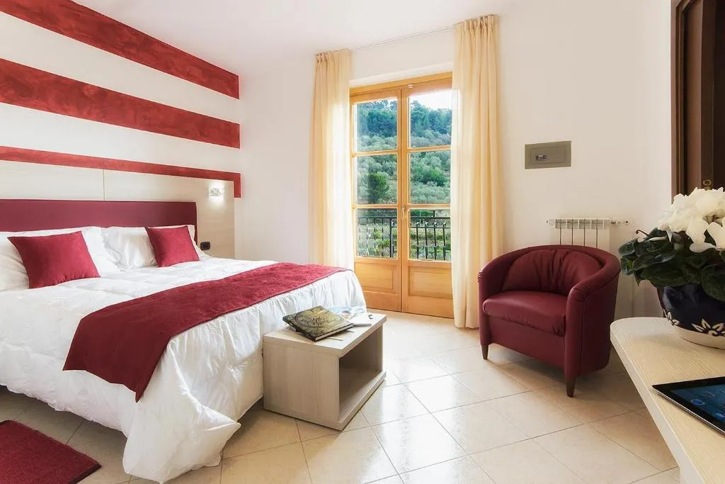 Camera matrimoniale con parete a strisce rosse, poltrona e porta finestra sul verde