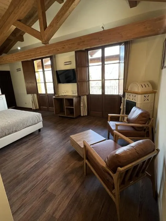 Ampia suite con soffitto in legno, poltrone in pelle e stufa in ceramica