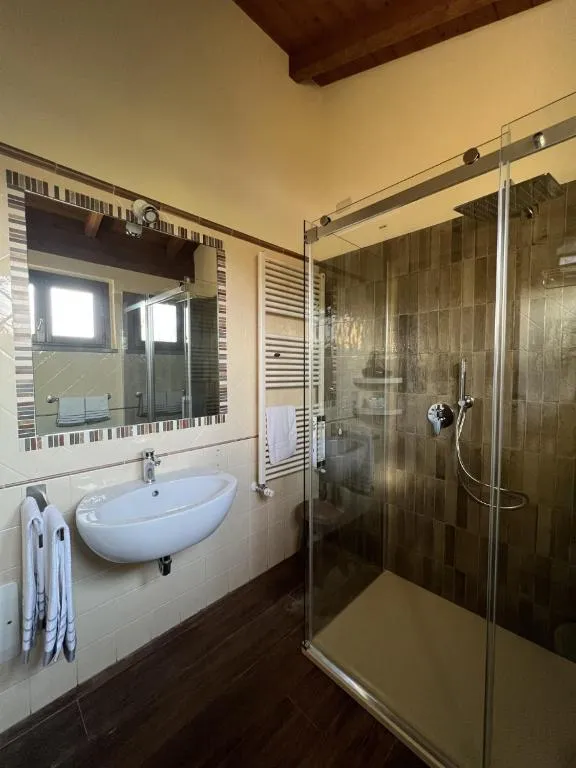 Bagno moderno con doccia in vetro, lavabo e scaldasalviette
