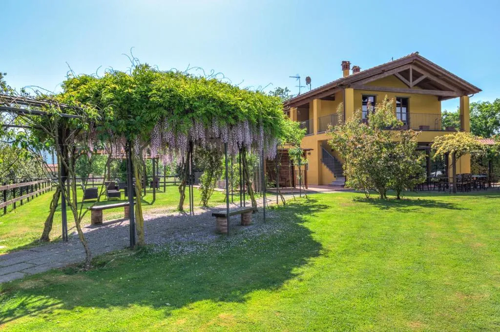 Casale giallo con pergolato di glicine e prato verde
