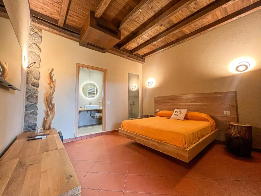 Camera elegante con letto matrimoniale arancione, travi in legno e bagno en suite