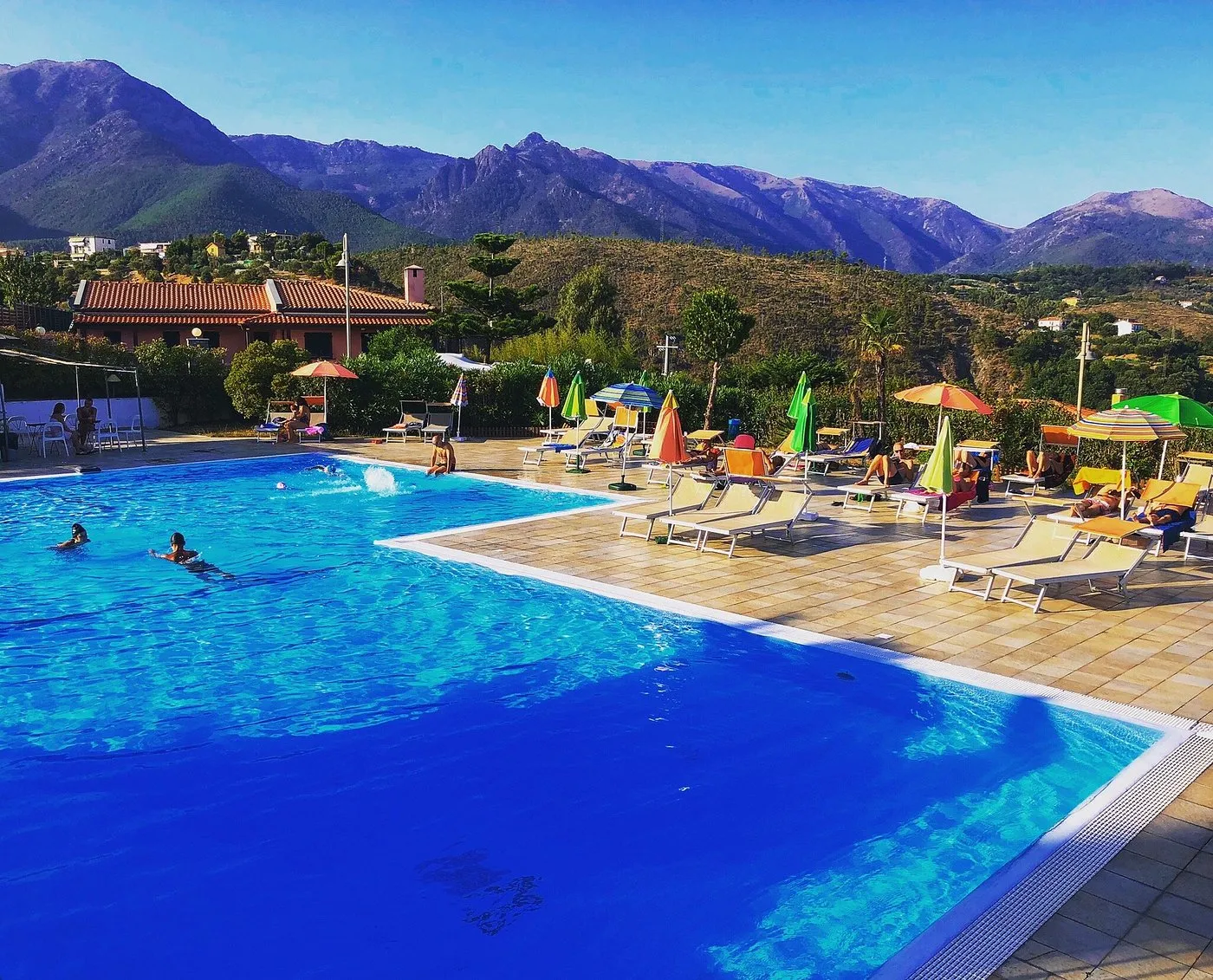 Piscina con lettini e ombrelloni colorati con vista sulle montagne