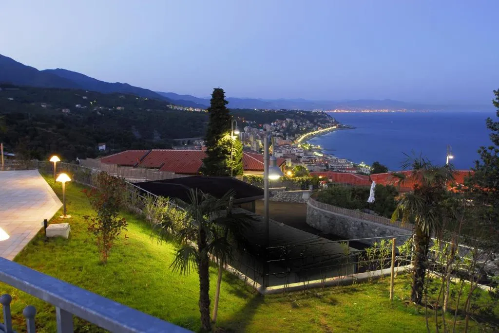 Vista serale sulla costa illuminata e sul mare dal giardino del residence