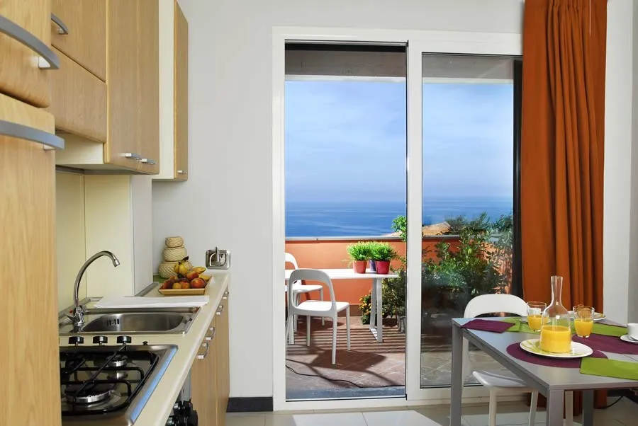 Cucina con tavolo apparecchiato e porta finestra affacciata sul mare