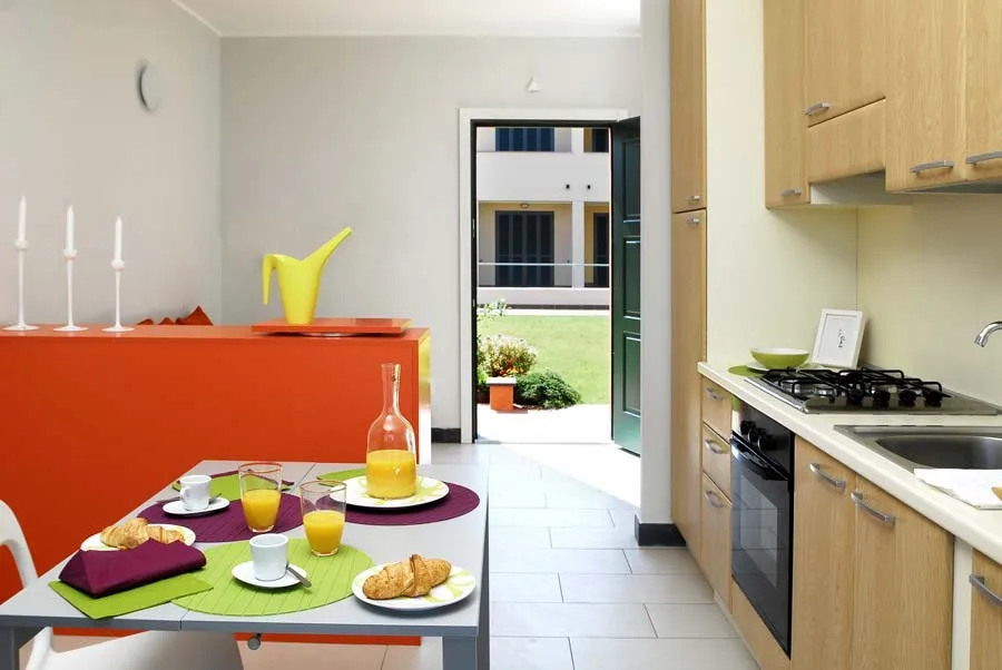 Cucina in legno chiaro con tavolo apparecchiato e porta sul giardino