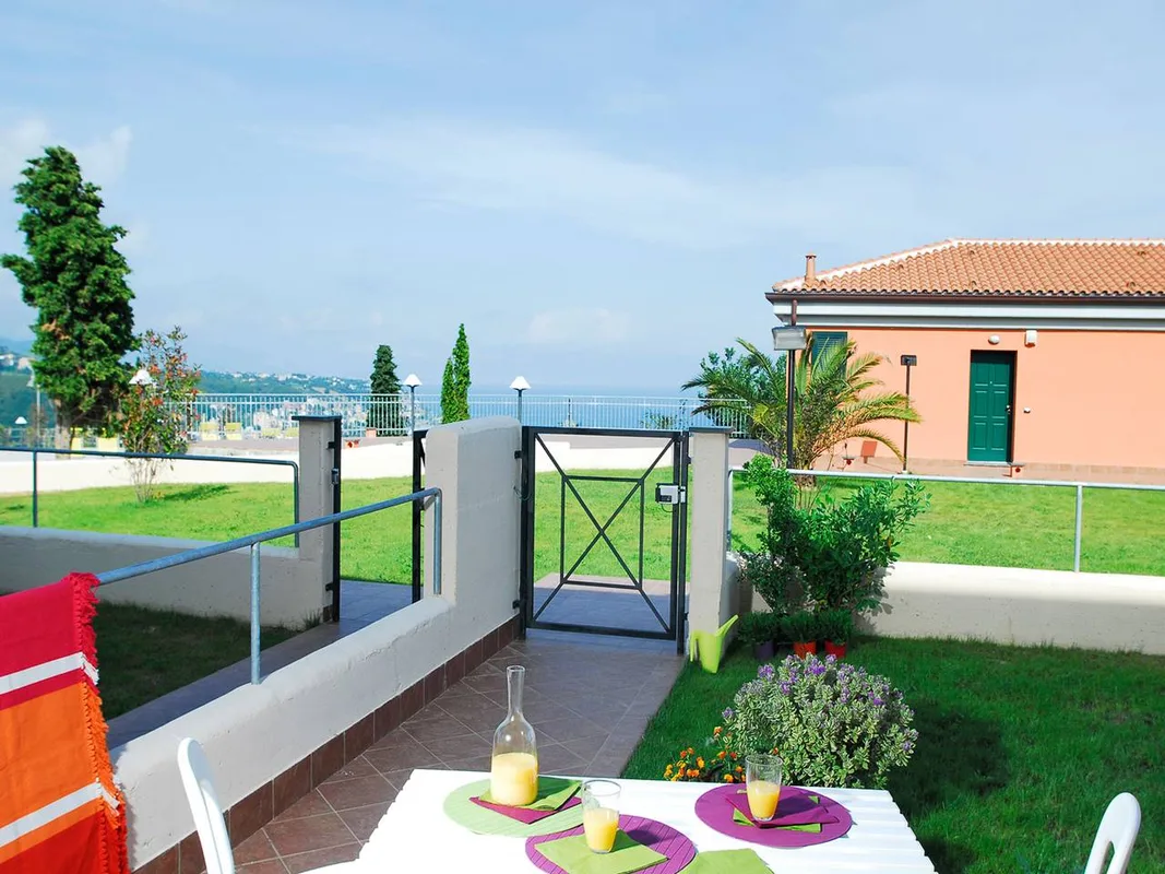 Terrazza con tavolo apparecchiato e vista sul giardino e sul mare