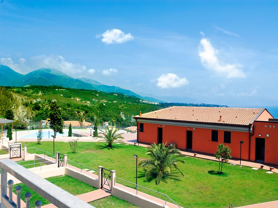 Vista panoramica del residence con piscina, giardini e montagne sullo sfondo