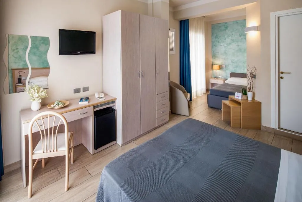 Camera spaziosa con letto matrimoniale, scrivania, armadio e zona soggiorno