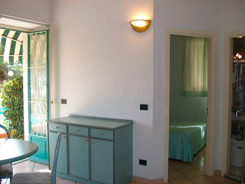 Soggiorno con credenza azzurra, porta finestra sul giardino e camera adiacente