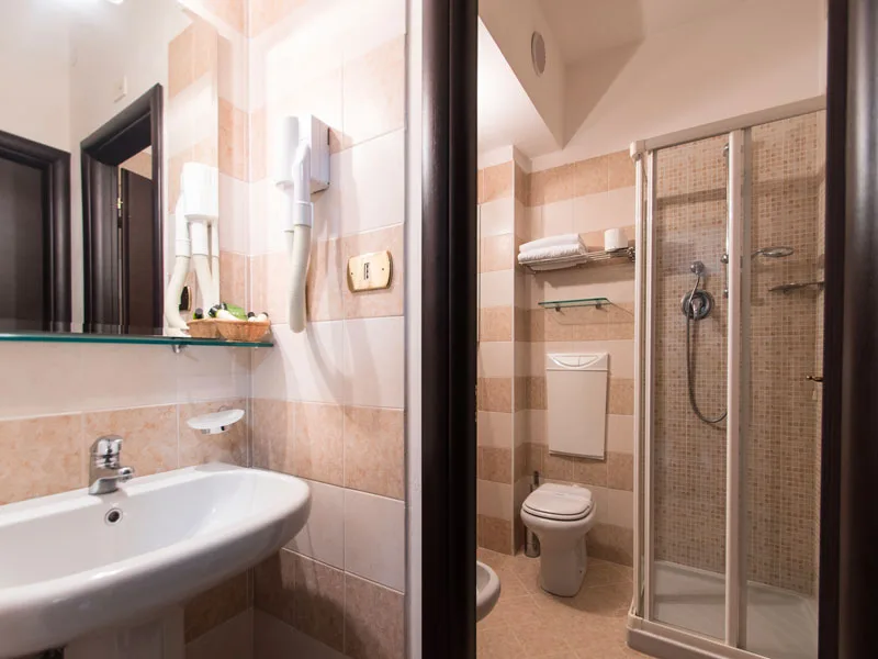 Bagno con lavabo, doccia e WC piastrellato in tonalità beige