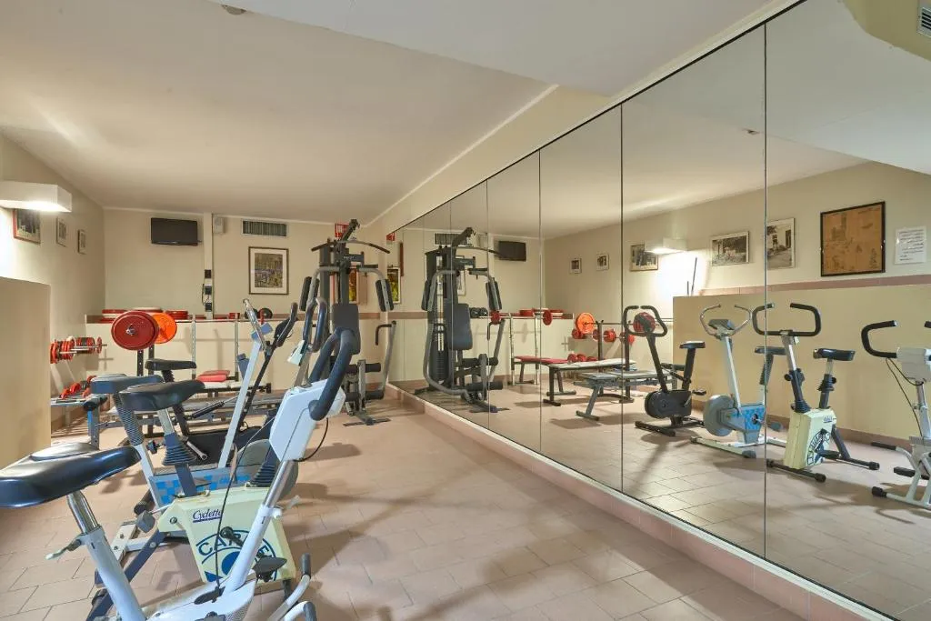 Sala fitness attrezzata con cyclette, pesi e macchinari, ampia parete a specchio
