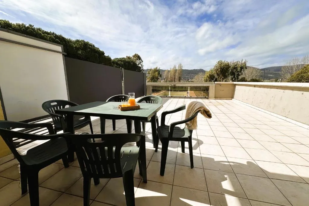Ampia terrazza con tavolo e sedie verdi affacciata sulle colline e la piscina