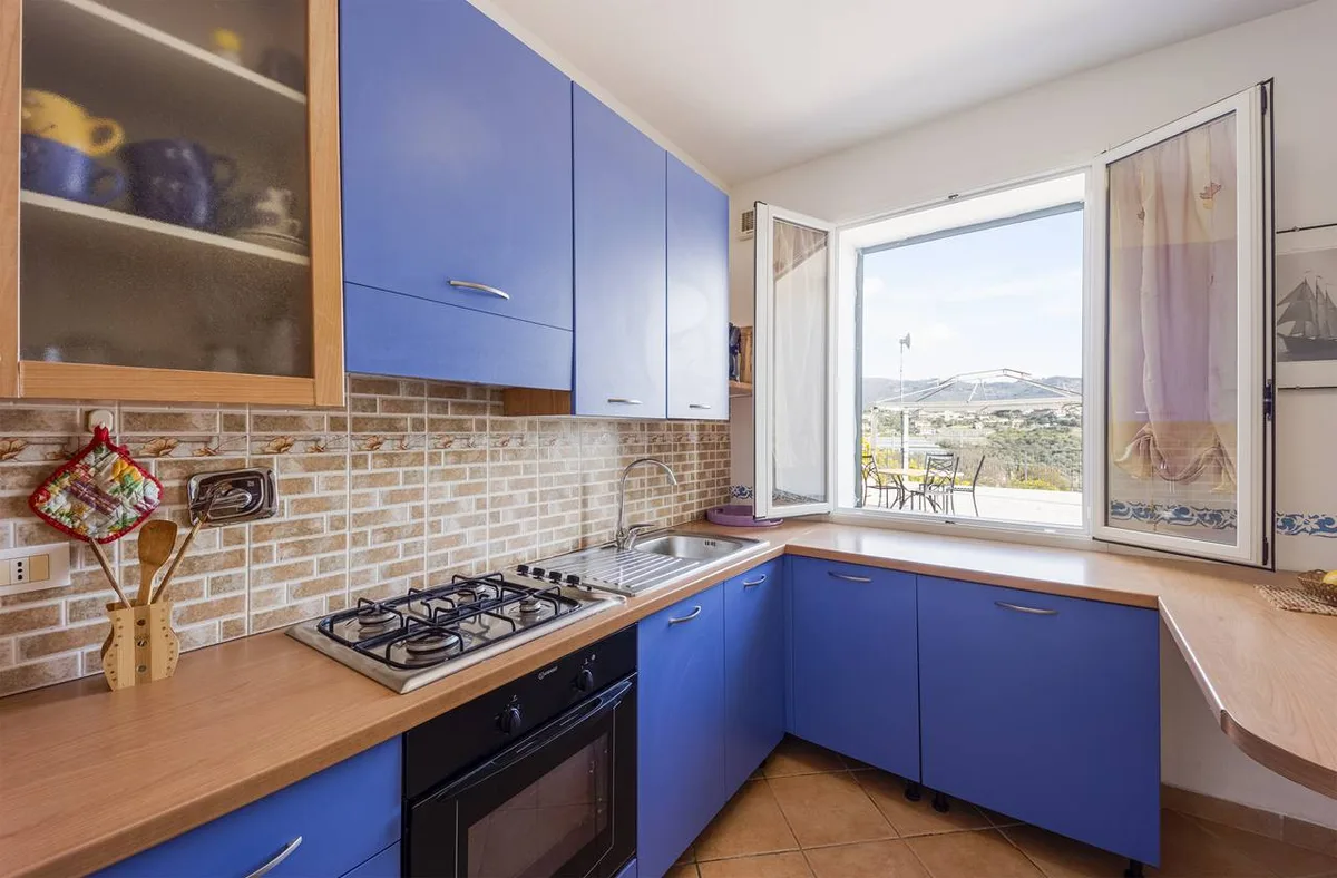 Cucina con mobili blu, piano cottura e finestra con vista sulle colline