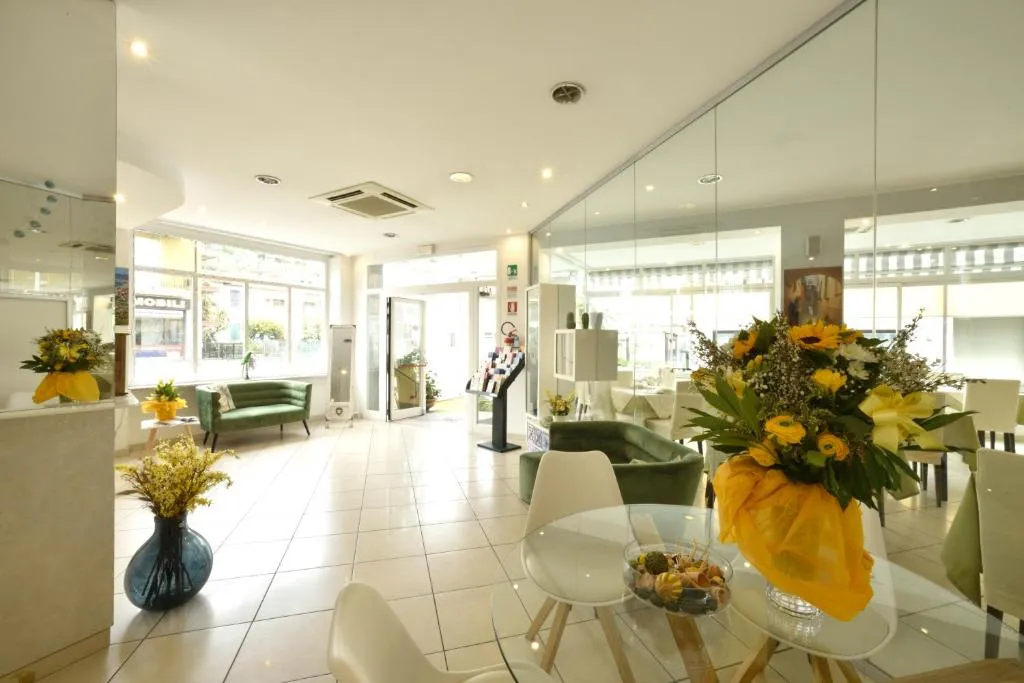 Hall dell'hotel con reception, divani verdi e composizioni floreali