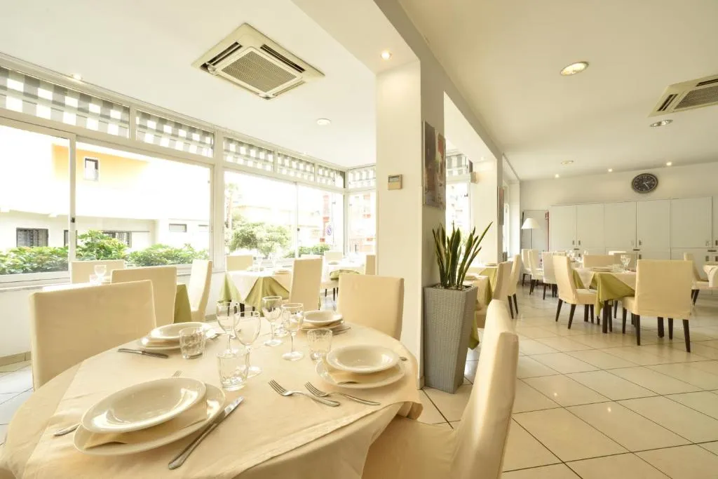 Sala ristorante luminosa con tavoli apparecchiati e sedie chiare