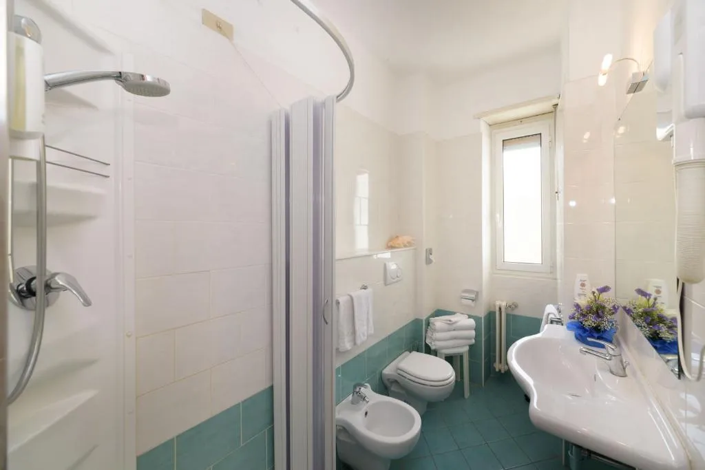 Bagno con doccia, bidet, lavabo e piastrelle verdi