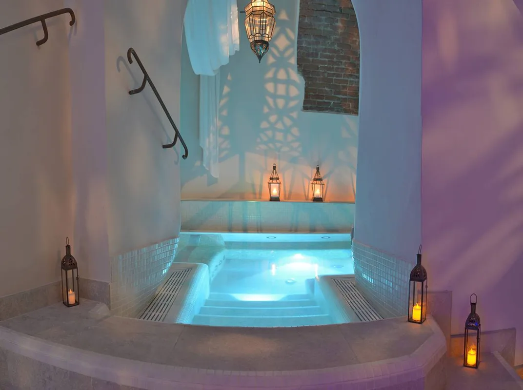 Vasca idromassaggio spa con illuminazione azzurra e lanterne a candela