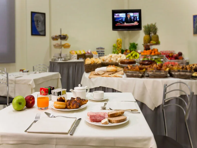 Tavolo della colazione con cornetti, succo e ricco buffet di frutta e dolci