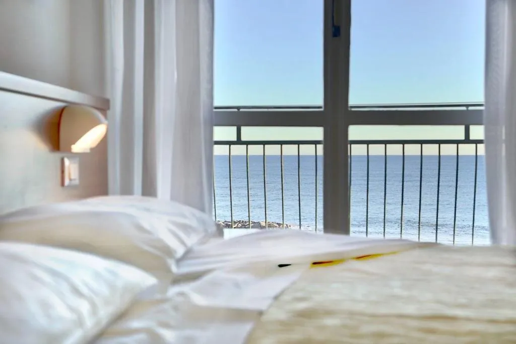 Letto con cuscini bianchi e balcone con vista panoramica sul mare