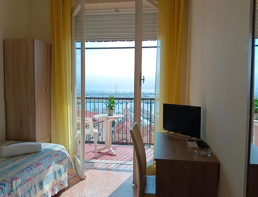 Camera con letto singolo, scrivania con TV e balcone con vista sul porto