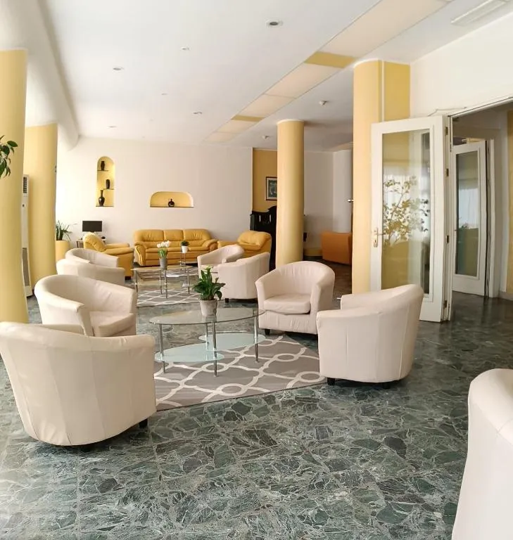 Hall dell'hotel con poltrone bianche, divani gialli e pavimento in marmo verde