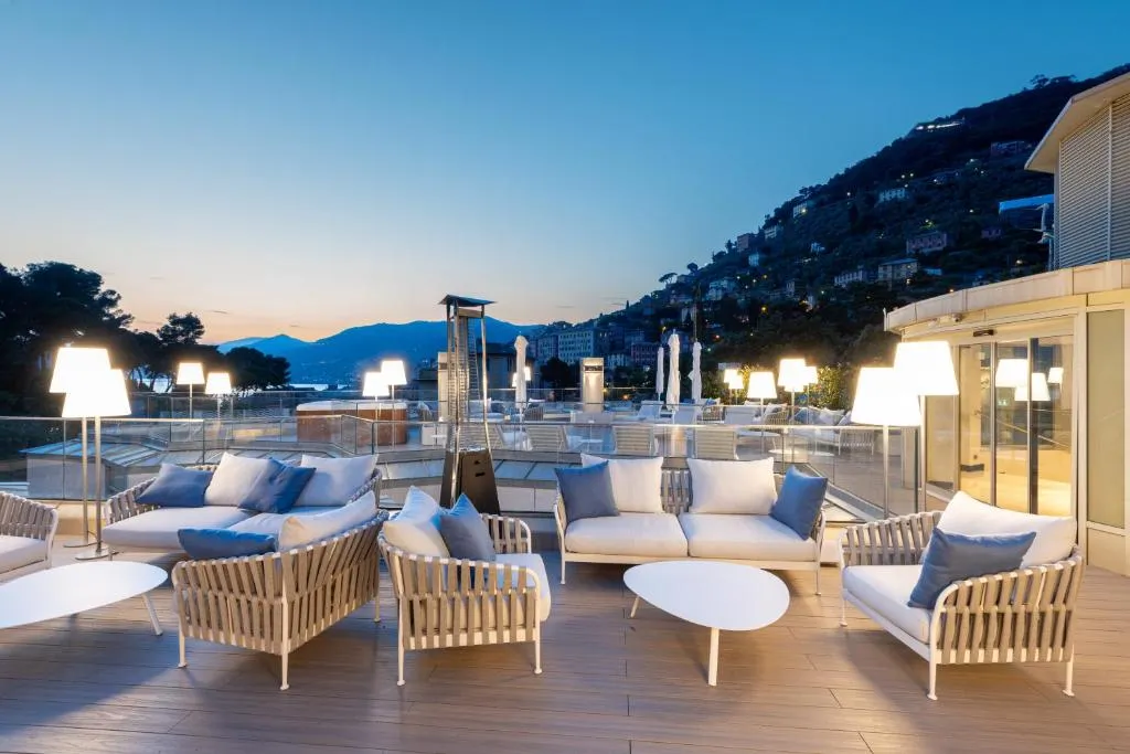Terrazza panoramica al tramonto con divani e poltrone, vista sulle colline e sul mare