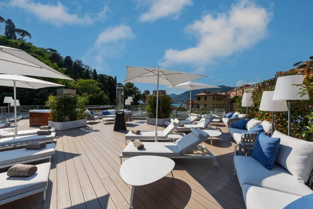Terrazza solarium di giorno con lettini, ombrelloni bianchi e divani affacciata sul paesaggio