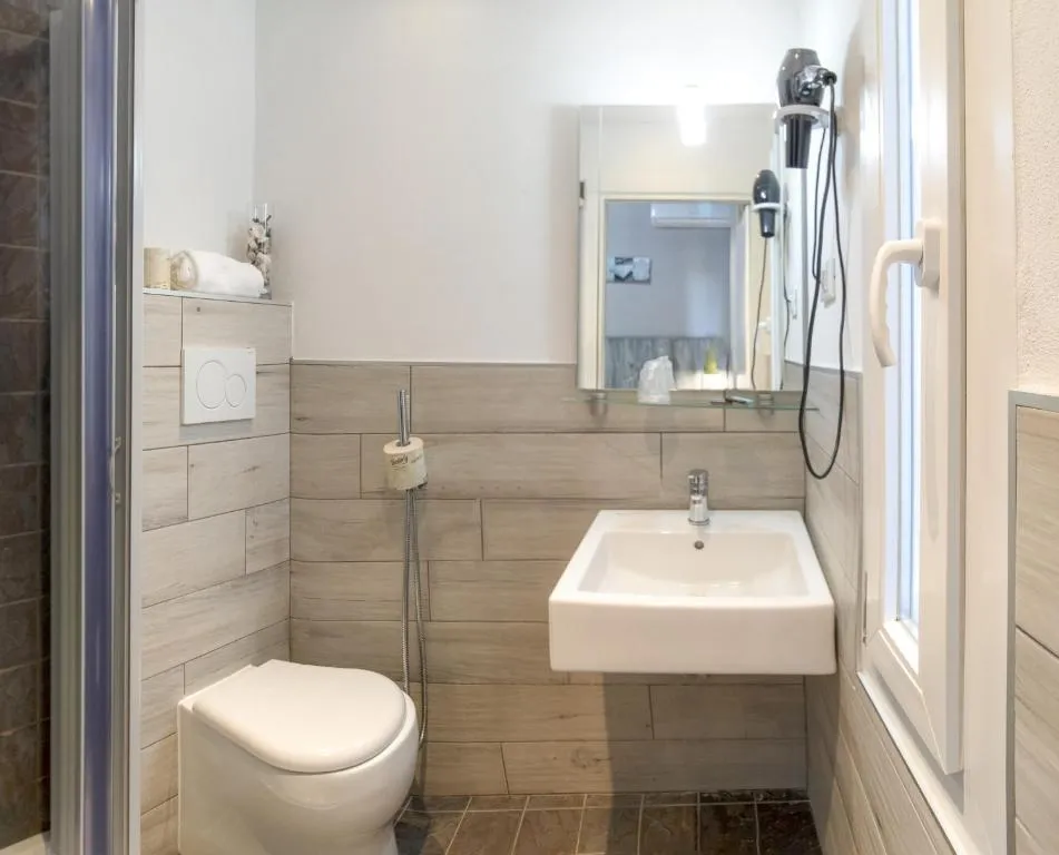 Bagno con doccia, sanitari, lavabo e specchio con asciugacapelli