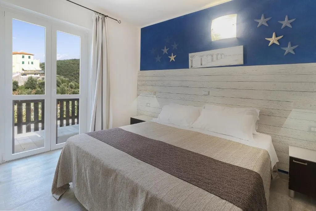 Camera con parete blu decorata e balcone con vista sulle colline