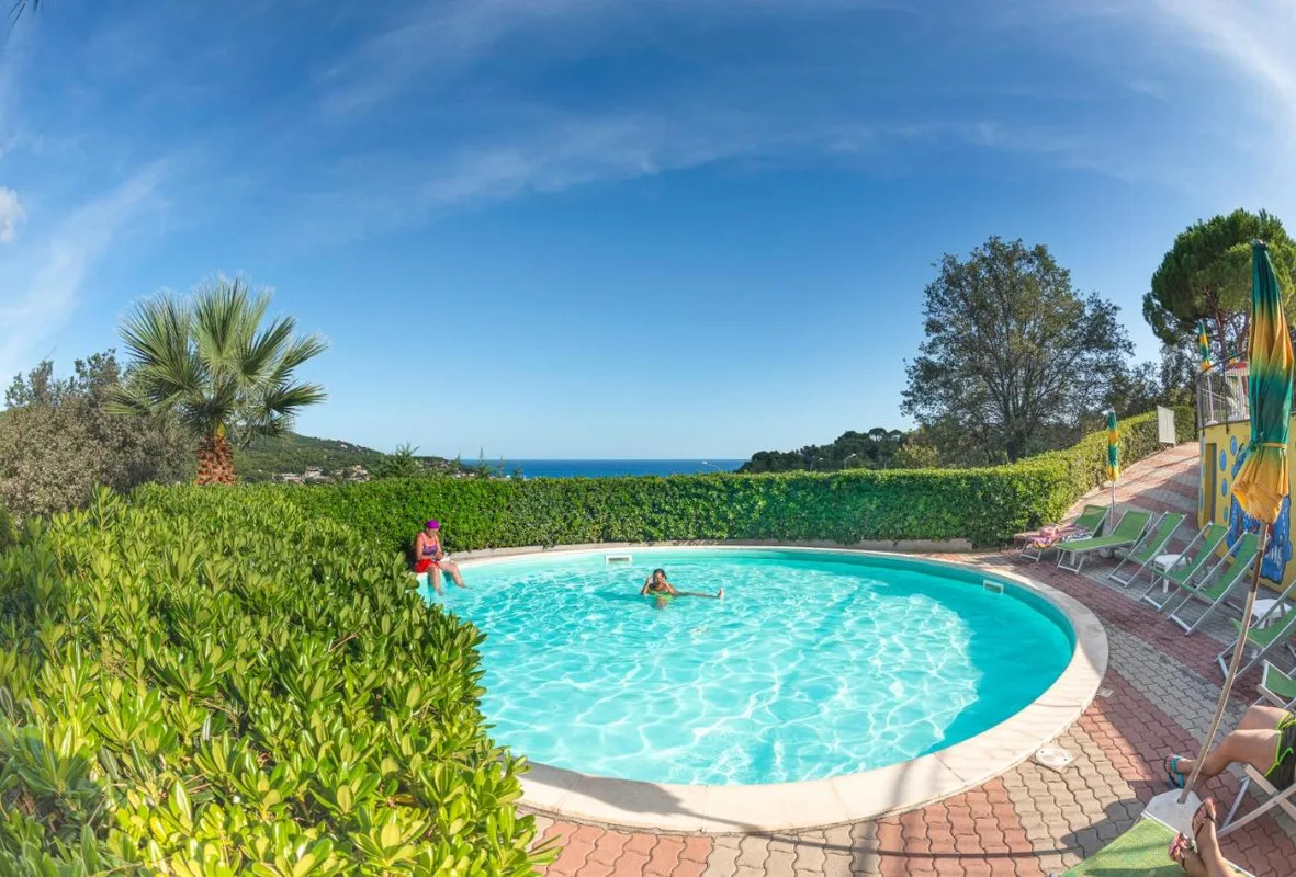 Piscina rotonda circondata dal verde con vista mare