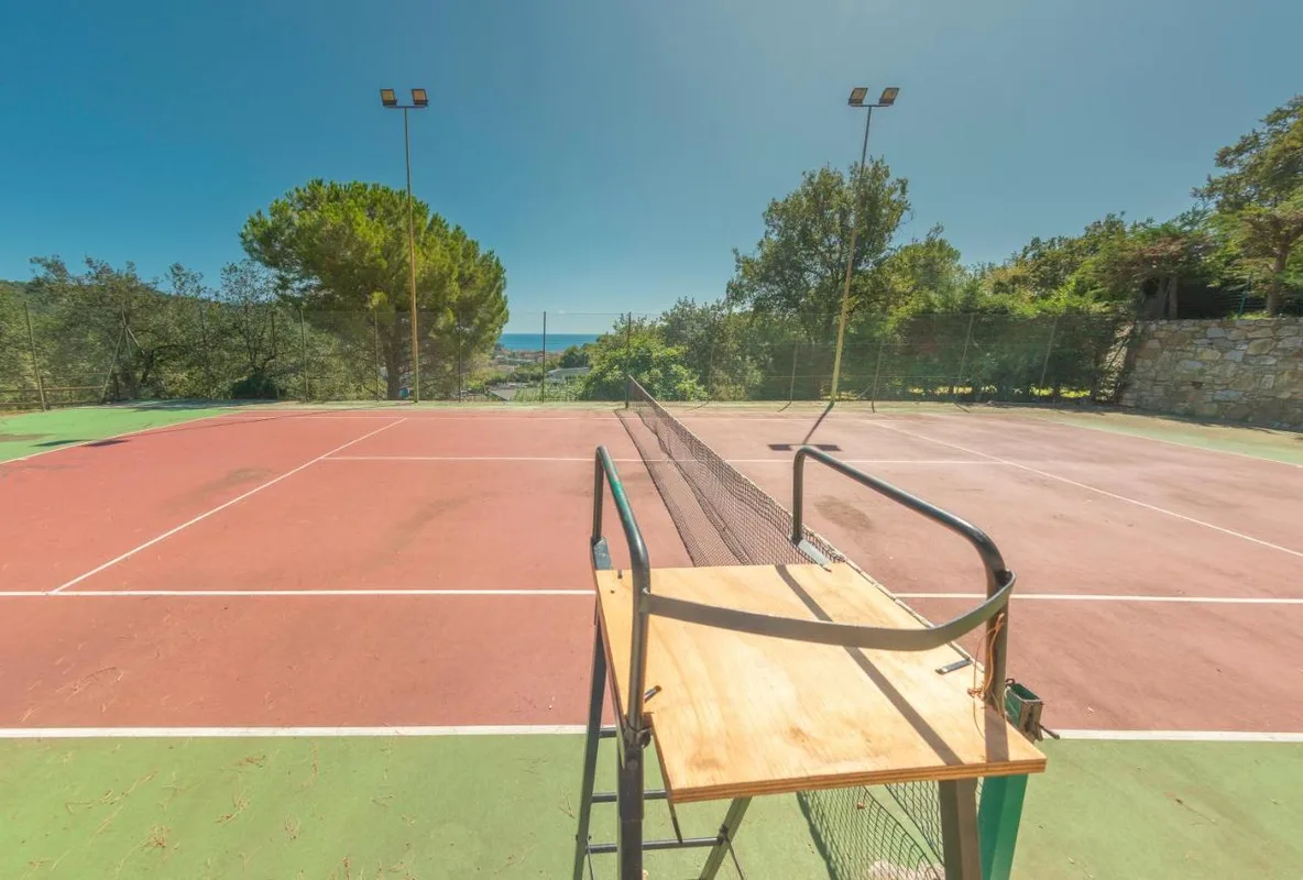 Campo da tennis con sedia arbitro e vista mare circondato dal verde