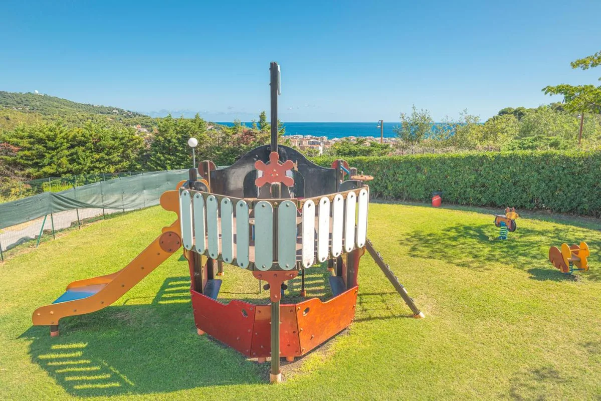 Area giochi per bambini su prato verde con vista mare e collina