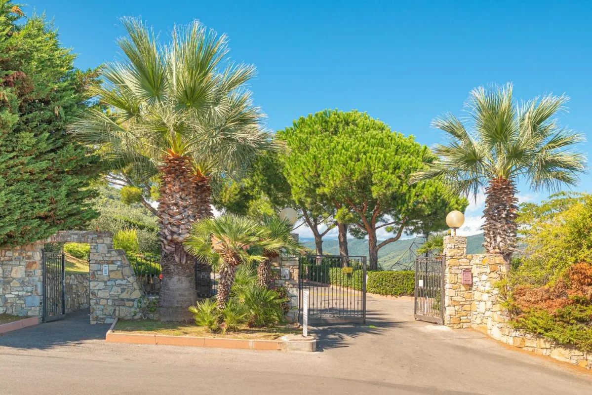 Ingresso del villaggio con cancello in ferro e palme