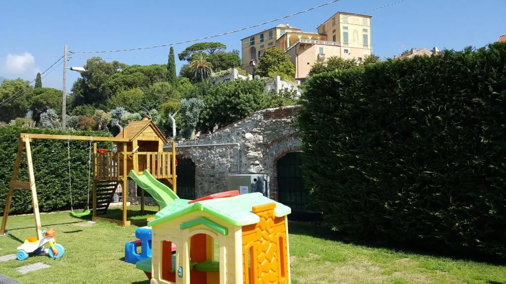 Area giochi per bambini all'aperto con scivolo, altalena e casetta colorata su prato verde