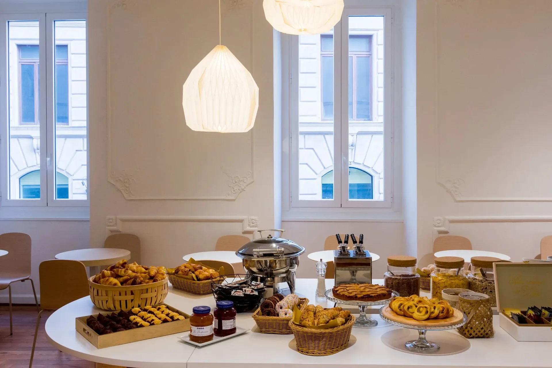 Buffet della colazione con cornetti, torte e marmellate vicino alle ampie finestre
