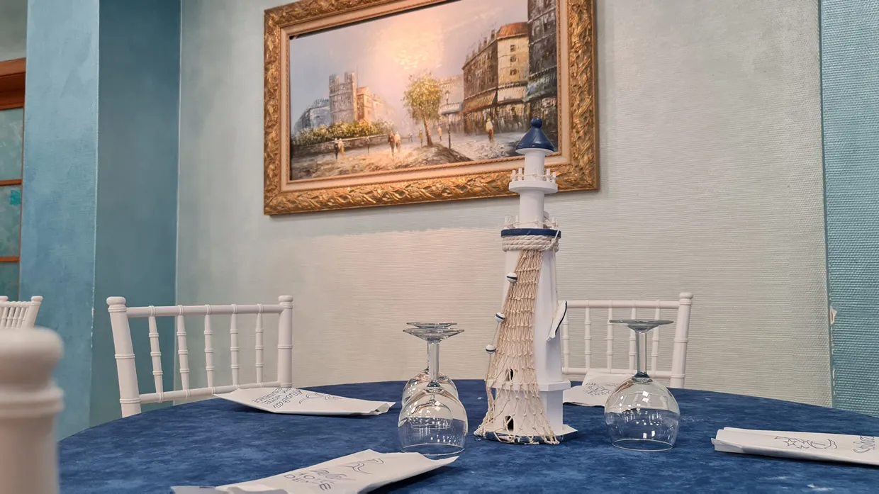 Tavolo apparecchiato con decorazione a faro e quadro alla parete