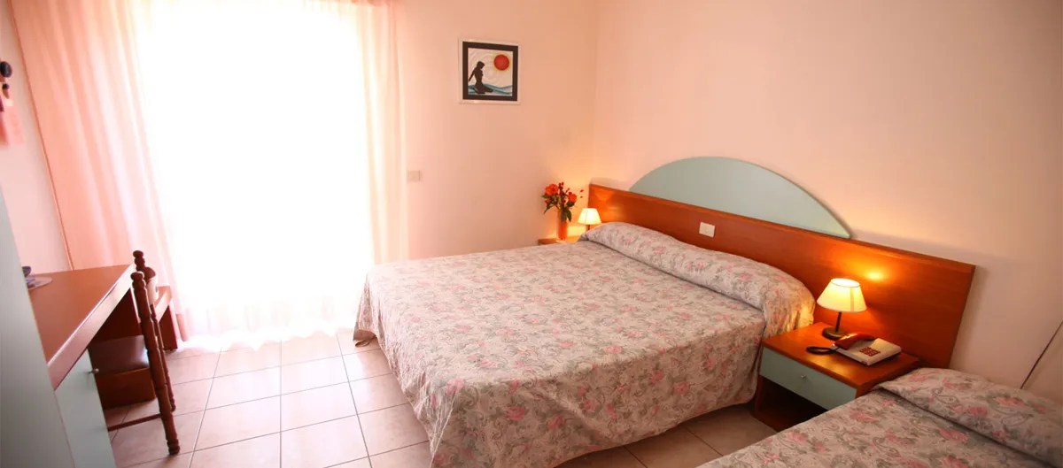 Camera matrimoniale con letto aggiunto, scrivania e ampia finestra luminosa