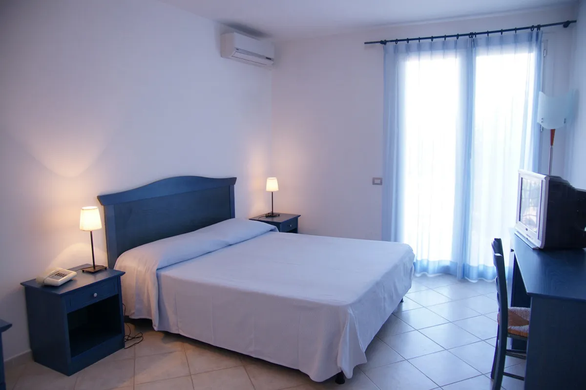 Camera da letto matrimoniale luminosa con arredi blu e ampia finestra