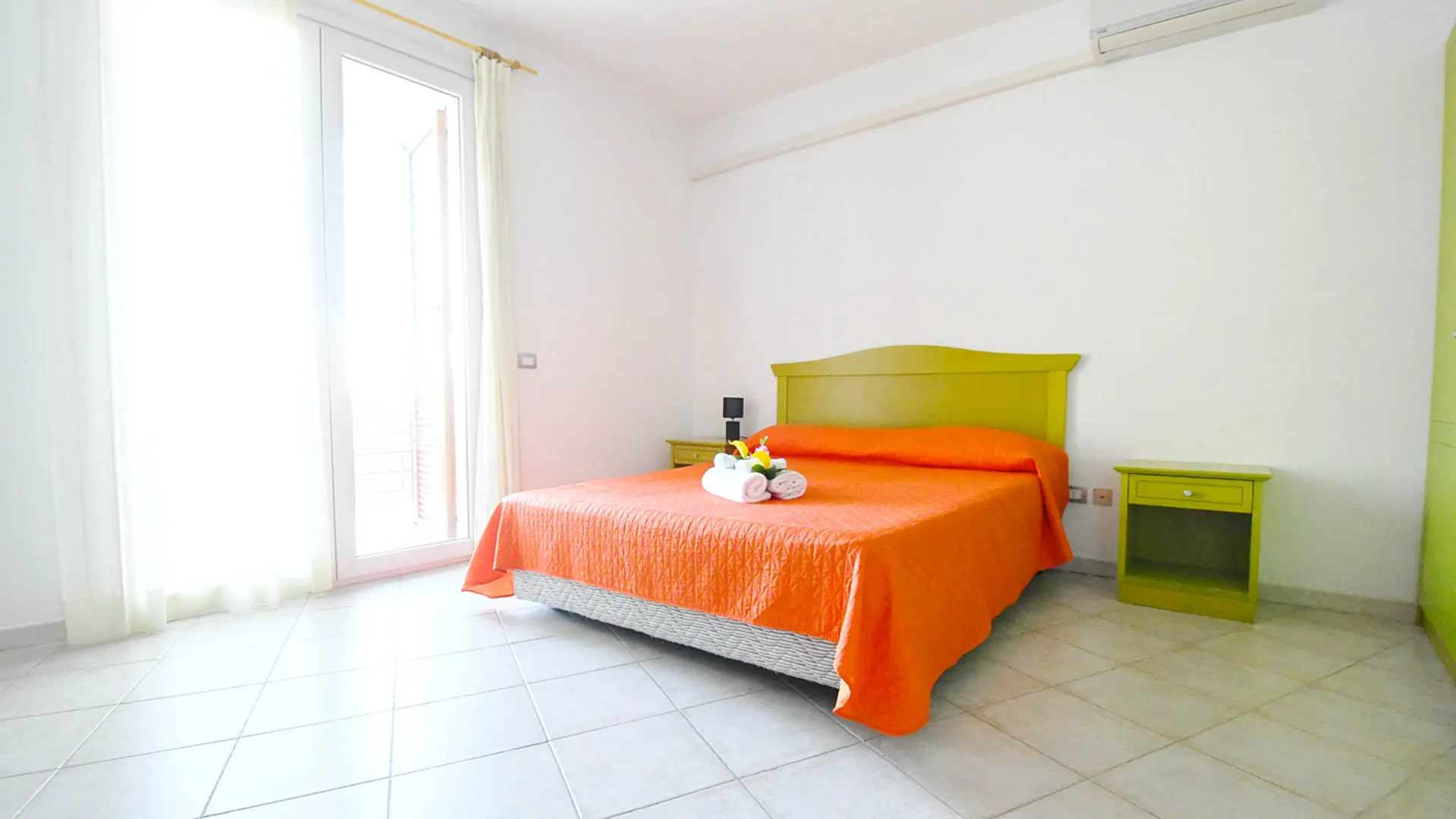 Camera da letto matrimoniale con copriletto arancione e mobili gialli
