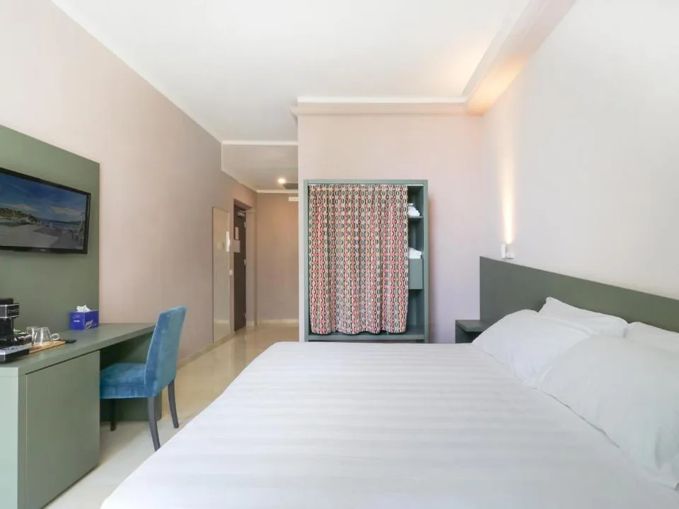 Camera con letto matrimoniale, scrivania, sedia blu e angolo guardaroba