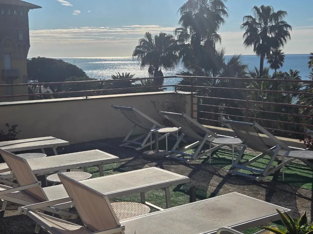 Terrazza solarium con lettini e vista sul mare con palme