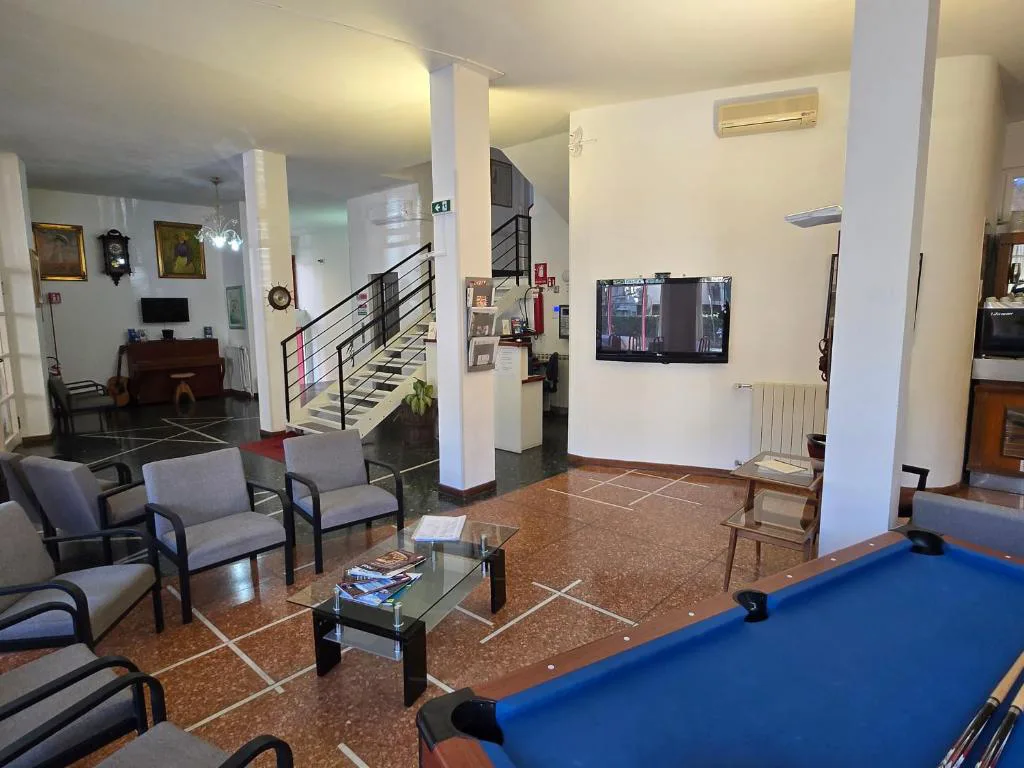 Hall dell'hotel con poltrone, tavolo da biliardo, TV e scala interna