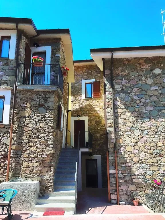 Cortile in pietra con scalinata di accesso e balconi fioriti