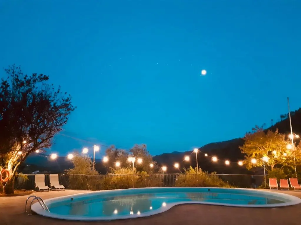Piscina illuminata di sera con luci decorative e luna nel cielo